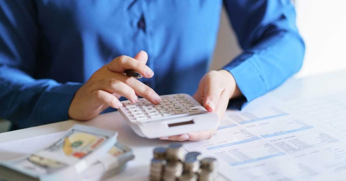 An accountant reviewing a business earnings statement with a calculator and financial documents on the desk