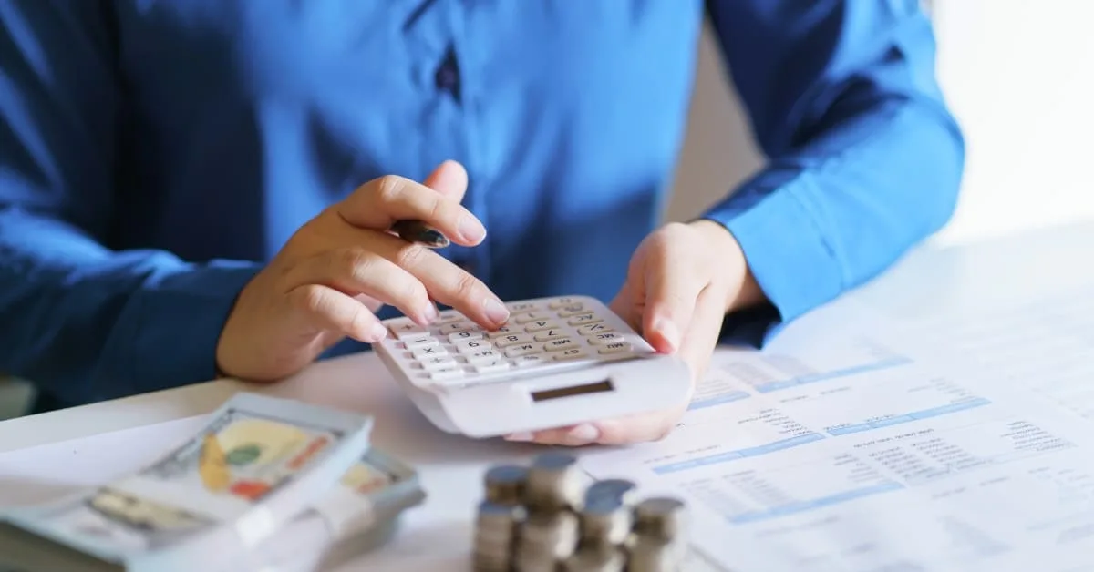 An accountant reviewing a business earnings statement with a calculator and financial documents on the desk