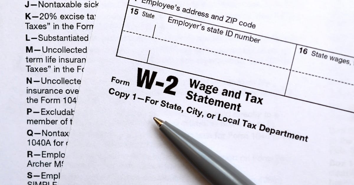 A close-up of a professionally edited W2 form with a pen and eyeglasses on the desk.